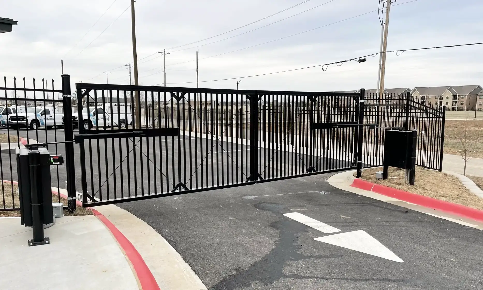Black iron gate access across parking lot
