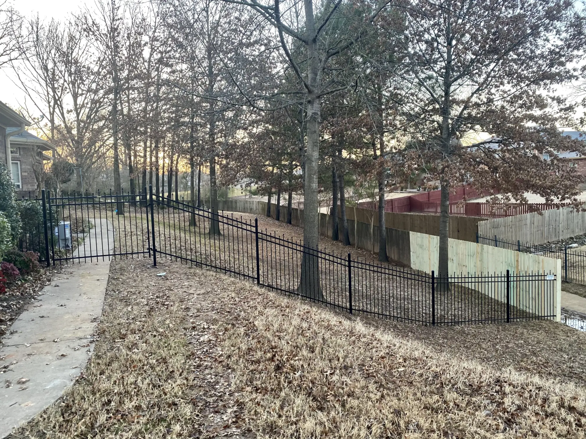 Residential black iron fence connecting to wood fence